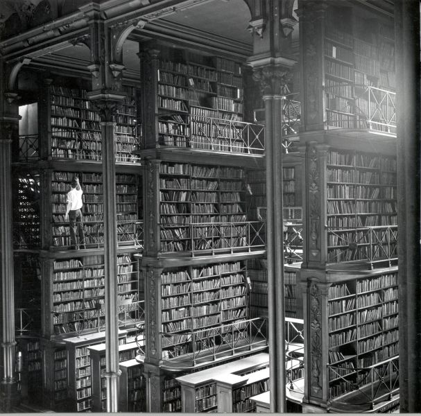 Mężczyzna przeglądający książki w potężnej bibliotece Cincinnatiego.Biblioteka została zniszczona w 1955r.